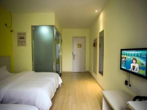 a hotel room with two beds and a flat screen tv at 7 Days Premium Suzhou Mudu Ancient Town in Suzhou