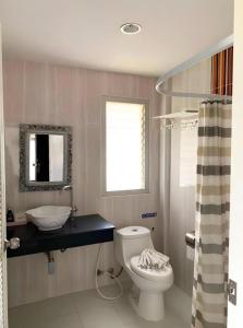 a bathroom with a toilet and a sink and a mirror at Rittiboon Vintage Hotel in Phrae