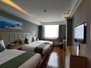 a hotel room with two beds and a flat screen tv at GreenTree Inn Hami Railway Station Bayi Road in Qumul +126 photos