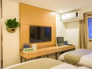 a hotel room with a desk with a tv and a bed at GreenTree Inn Beijing Dongcheng District Wangfujin South Luogu Lane Houhai Express Hotel in Beijing
