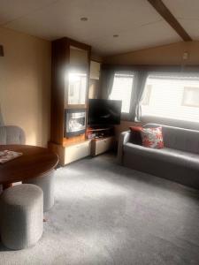 a living room with a couch and a table at Your Happy Place - 8 Berth Caravan 5 minutes from lovely sandy beach in Heacham