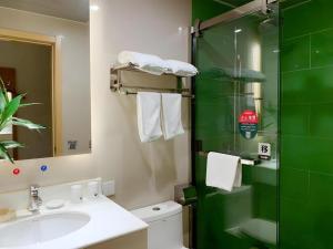a bathroom with a sink and a glass shower at GreenTree Inn Suzhou Changshu North Haiyu Road Changhui Square Express Hotel in Changshu +240 photos
