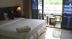 une chambre avec un grand lit blanc et un balcon dans l'établissement Kamala Phuyai Resort, à Kamala Beach