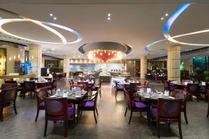 a restaurant with tables and chairs and a chandelier at Expo Garden Hotel in Kunming