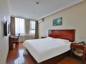 a bedroom with a large white bed and a desk at GreenTree Inn Beijing Daxing Xingye Street Liyuan Business Hotel in Beijing