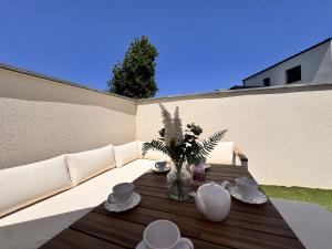 una mesa de madera con un jarrón de flores en el patio en La Bella Rosa - Direct circuit - Piscine - Climatisation, en Le Mans