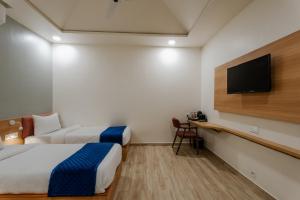 een hotelkamer met twee bedden en een flatscreen-tv bij Prarambh By Siara in Nadiād