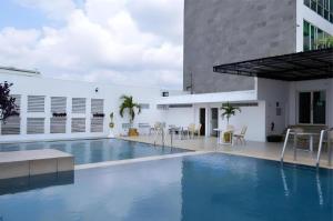 a swimming pool with chairs and a building at Grand Daira Hotel Palembang in Palembang