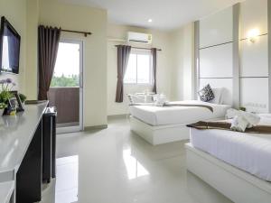 Un baño grande y blanco con dos camas y una bañera. en The Rich Residence, en Ban Tha Kup