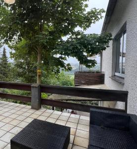 a patio with two chairs and a tree and a fence at Fuldablick Melsungen 1 in Melsungen