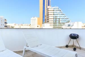 a white chair sitting on a balcony with a grill at Tonis City Apartments in St Julian's
