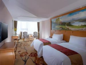 a hotel room with two beds and a television at Vienna International Hotel Guangzhou Huangpu in Guangzhou +137 photos