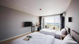 済州市にあるSallys Jeju Hotelのベッドが2つと大きな窓があるホテルの部屋 +185枚の写真
