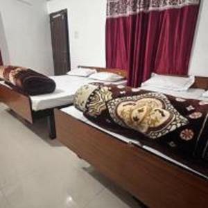 Duas camas individuais num quarto com uma cortina vermelha em Shree Mahakaal Inn by StayApart em Gupta Kāshi mais 14 fotografias