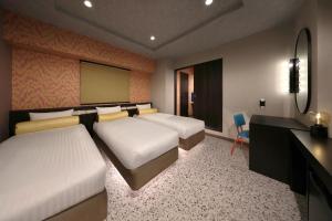 a hotel room with two beds and a desk and a desk at Nipponbashi Luxe Hotel in Osaka