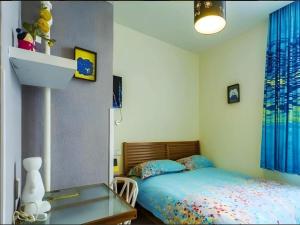 a bedroom with a bed and a table and a mirror at Dalian Household Theme Hotel Huanghe Road Branch in Dalian