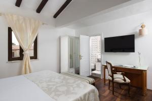 a bedroom with a bed and a desk and a television at Villa Luka in Višnjan