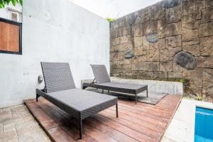 Dos sillas y una mesa en una terraza de madera. en 5BR Villa Naga Sanur, en Sanur 7 fotos más