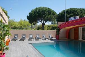 a hotel with a swimming pool and lounge chairs at Hotel & Spa Gil de France Cap d'Agde in Cap d'Agde