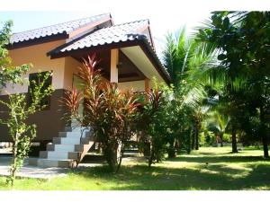 a house with stairs in front of a yard with trees at Suvimon Resort in Si Maha Phot
