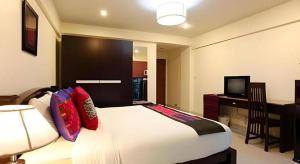 a bedroom with a bed and a desk and a television at The Xym Hotel in Chiang Mai