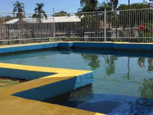 uma piscina de água com um passeio amarelo em frente a uma cerca em Boggabilla Motel em Boggabilla