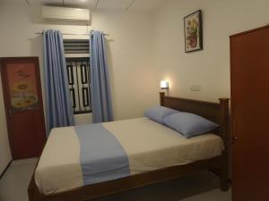 米瑞莎Coralworld Hotel的一间卧室，有一张床和一扇带蓝色窗帘的窗户 更多83张照片