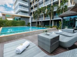 a swimming pool with wicker furniture next to a building at B2 Krabi Premier Hotel in Ao Nang Beach