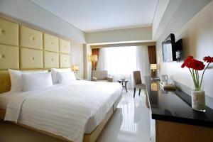 Un dormitorio con una gran cama blanca y un escritorio. en Hotel Santika Makassar, en Makassar 114 fotos más