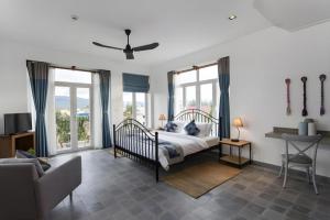 a bedroom with a bed and a couch and windows at Boutique Kampot Hotel in Kampot