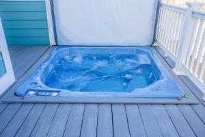 a blue hot tub on a deck with a porch at 4000 - Fragile Magic in Kitty Hawk