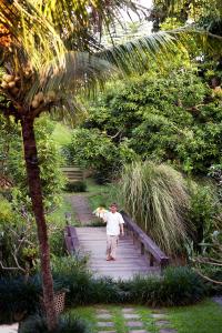 a man walking across a wooden bridge in a garden at Kalapa Boutique Resort & Yoga in Canggu +81 photos