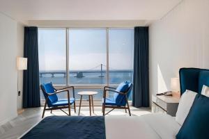a bedroom with a bed and two chairs and a table at Hotel Homers in Busan