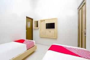 a bedroom with two beds and a tv on the wall at Super OYO 2436 Hotel Kencana in Tegal