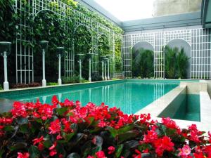 Una piscina en un edificio con flores rojas. en d'primahotel Bandung, en Bandung