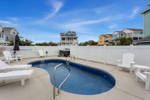 a swimming pool on a patio with white fence and chairs at 1013 - High Tides and Philly Forever in Corolla