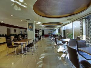 a dining room with tables and chairs in a building at Raffleshom Hotel in Bandung