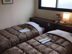 a room with two beds in a room with a phone at HotelNewYama in Nagano