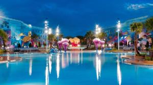 a large pool of blue water with pink umbrellas at Disney's Art Of Animation Resort in Orlando
