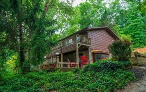 a house with a deck and red chairs in the woods at Whiskey Ridge in Sevierville