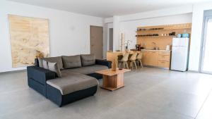 a living room with a couch and a table and a kitchen at White luxury apartment in Tríkala