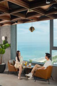 two people sitting at a table in a room with a window at PHUC LONG LUXURY Hotel Danang in Danang