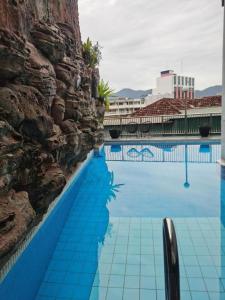 a swimming pool with blue water and a stone wall at Ritz Garden Hotel in Ipoh