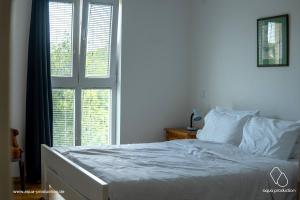 a white bed in a bedroom with a window at Apartman Damir in Malinska