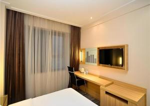 ein Hotelzimmer mit Schreibtisch und Fernseher in der Unterkunft City Comfort Inn Kunming Railway Station Guanshang in Kunming + 67 Fotos