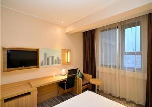 ein Hotelzimmer mit Schreibtisch und Fernseher in der Unterkunft City Comfort Inn Kunming Railway Station Guanshang in Kunming