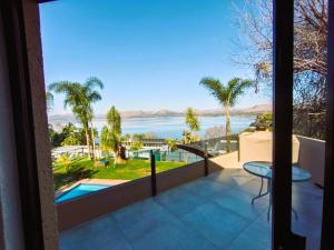 a balcony with a view of the water and palm trees at Letamo View - 5 bedroom house in Hartbeespoort