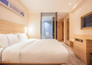 a bedroom with a large white bed and a television at City Comfort Inn Nanning Jinhu Plaza Langxi Metro Station Exhibition in Nanning +147 photos