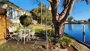 a patio with a table and chairs next to a lake at A Slice Of Paradise in Sussex Inlet