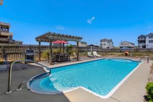 a pool with a pergola and a table and chairs at 4122 - Blue White Haven in Kitty Hawk